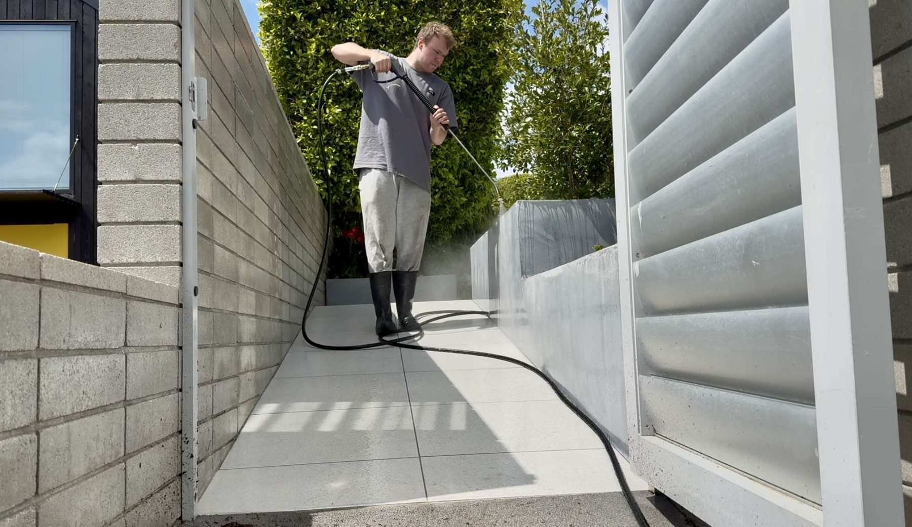 Operator soft washing a building in Auckland